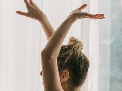 Silhouette of a person in a balancing yoga pose against a soft light.